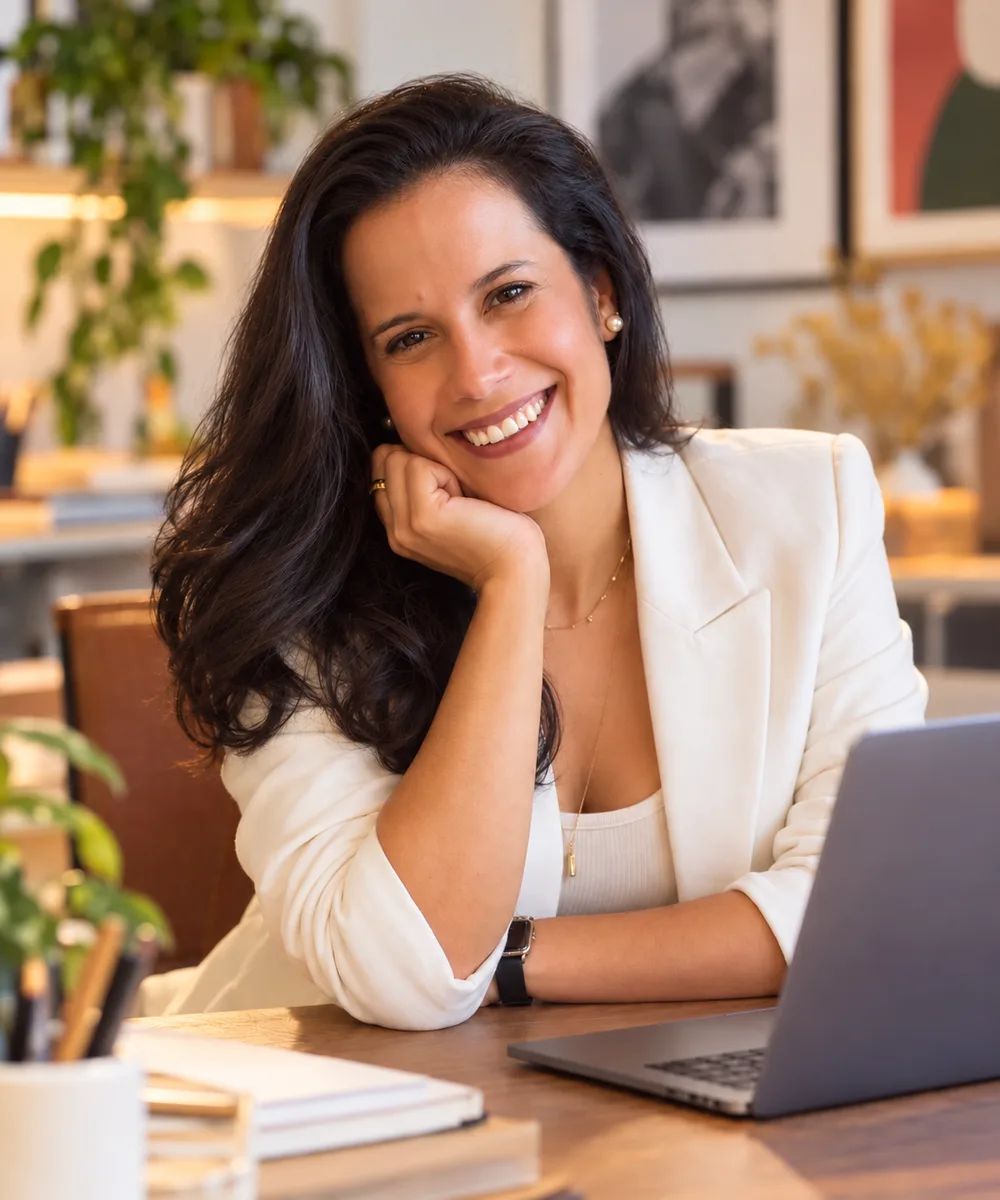 Maria Alice, social media e estrategista digital, sorrindo à mesa de trabalho